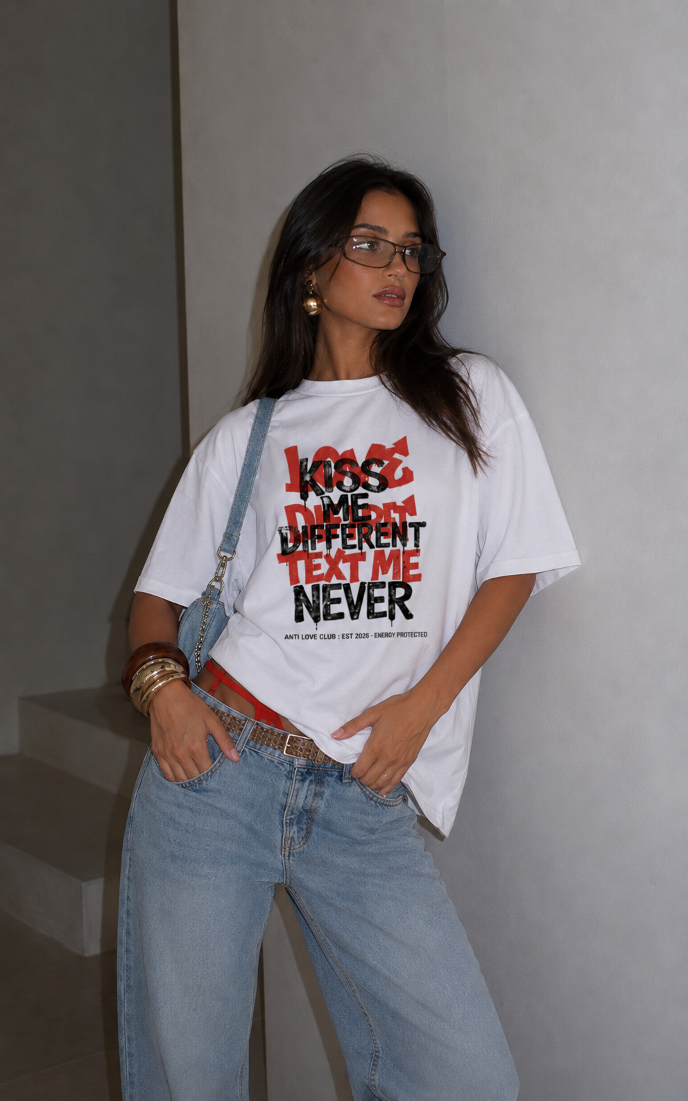 Woman posing with hands in pockets wearing oversized white graphic t-shirt front graphic print, relaxed fit urban graphic streetwear look