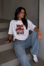 Woman sitting on stairs wearing oversized white graphic t-shirt front view featuring Kiss Me Different Text Me Never design, casual urban streetwear outfit