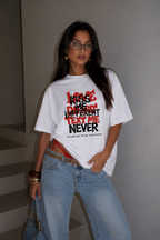 Woman facing camera wearing oversized white graphic t-shirt front chest graphic with Kiss Me Different Text Me Never print, relaxed streetwear fashion