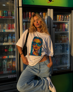 Woman posing with hand in pocket wearing oversized white graphic t-shirt featuring colorful braided girl print, relaxed fit urban streetwear look