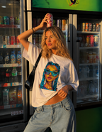 Woman balancing soda can on her head wearing oversized white graphic t-shirt front view with vibrant braided girl artwork, modern streetwear fashion