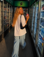 Woman walking away holding soda can wearing oversized white graphic t-shirt back view with clean white back, relaxed fit streetwear fashion