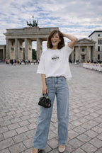 female model full body front view wearing oversized white graphic streetwear t shirt own your reality minimal graphic streetwear outfit
