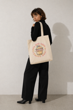 model over shoulder pose wearing canvas tote bag cute drink illustration soft aesthetic streetwear outfit