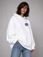 female model angled pose wearing oversized white graphic hoodie minimalist urban streetwear outfit