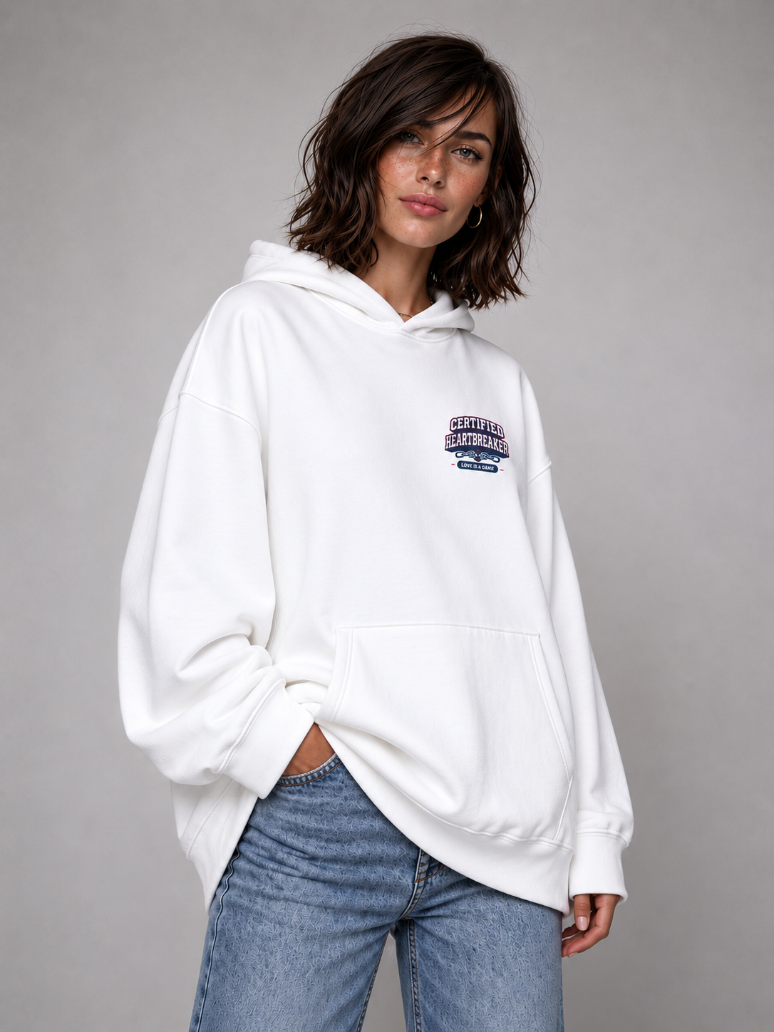 female model angled pose wearing oversized white graphic hoodie minimalist urban streetwear outfit