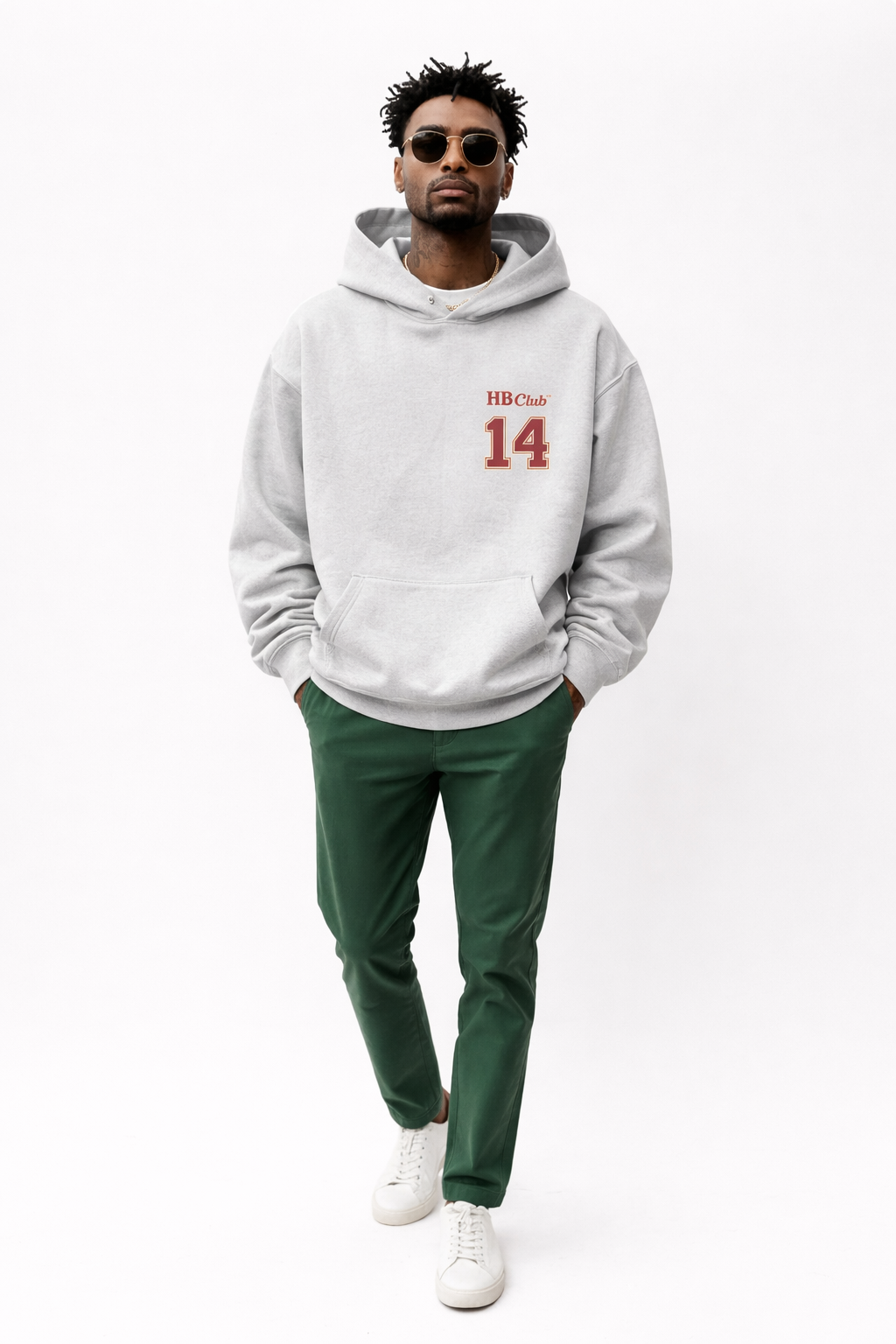 Male model in grey oversized hoodie with small red “14” chest print, casual streetwear look with green trousers.