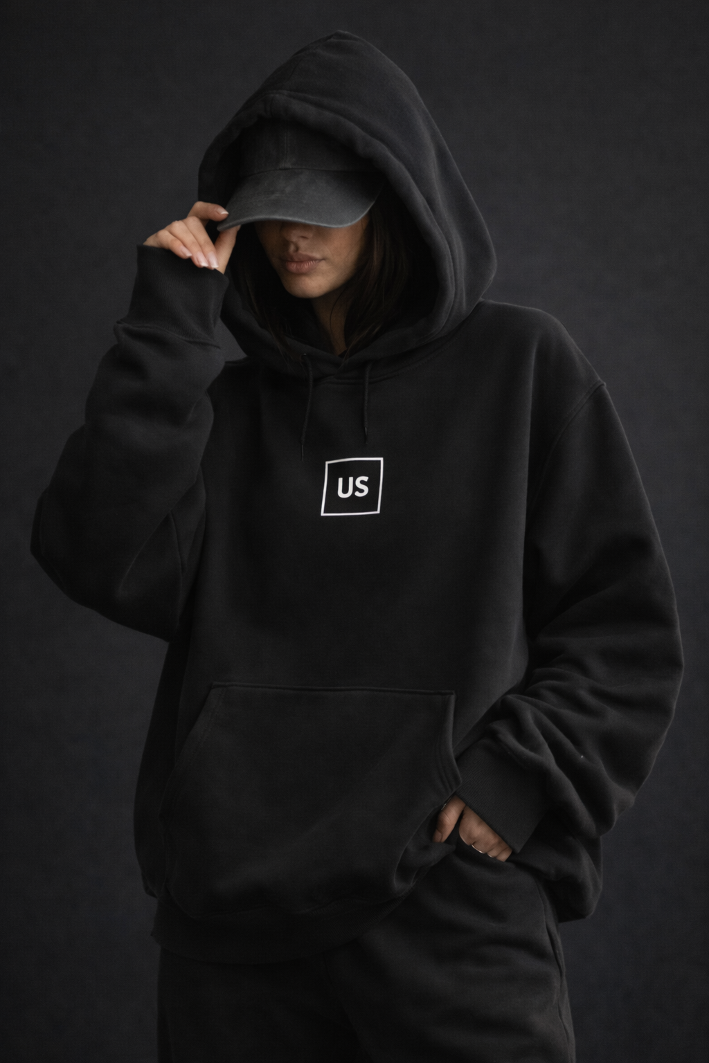 Female model front pose wearing oversized black graphic streetwear hoodie minimal chest logo streetwear fashion