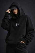 Female model casual pose wearing oversized black graphic streetwear hoodie minimal chest graphic streetwear outfit