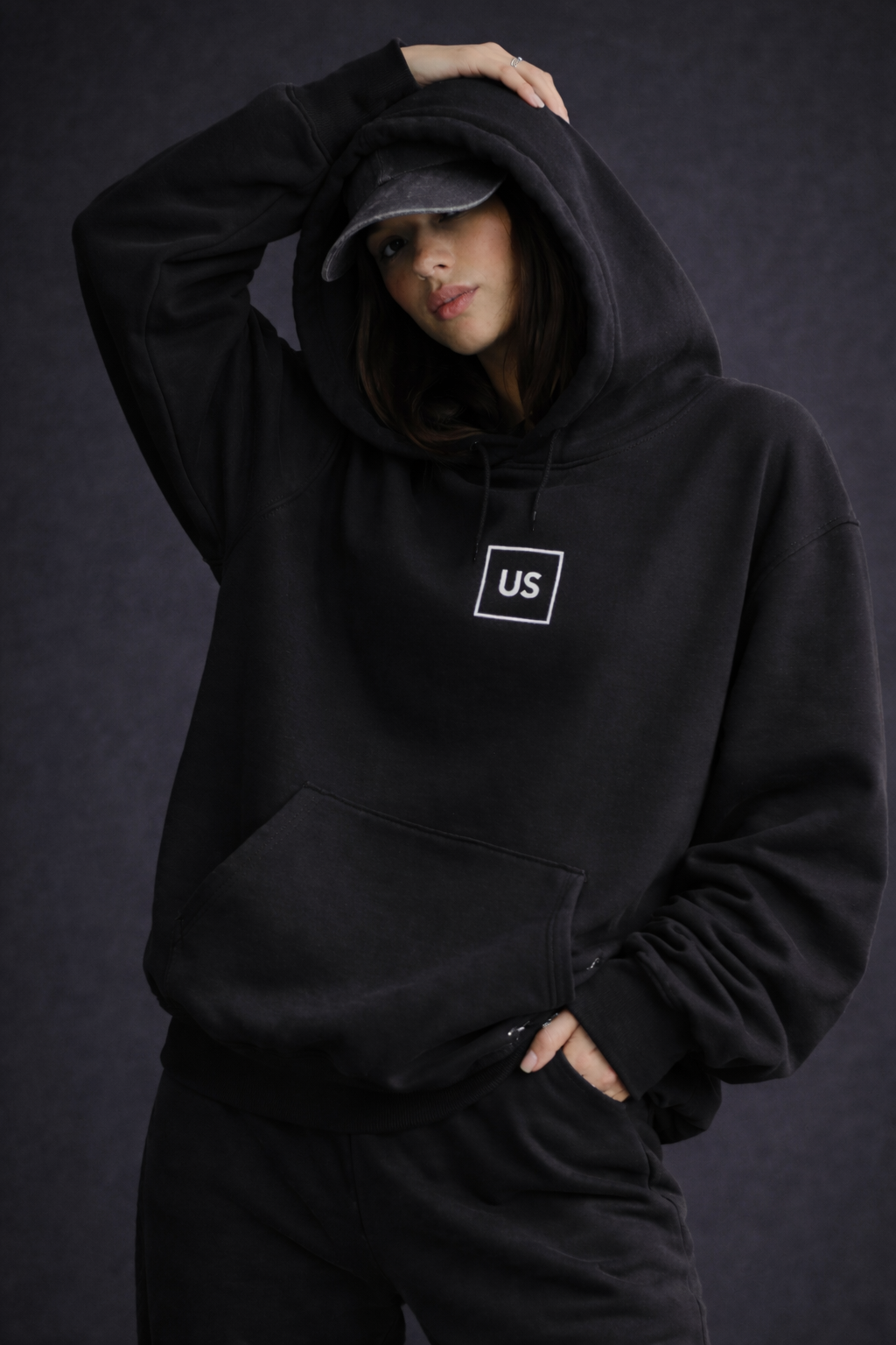 Female model hood up pose wearing oversized black graphic streetwear hoodie urban streetwear fashion