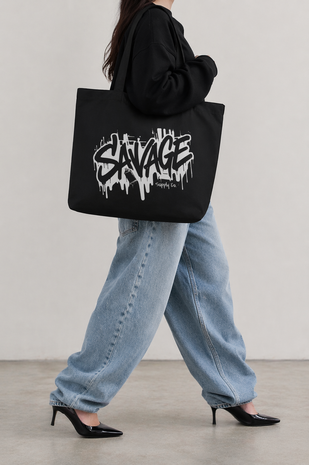 model walking side view carrying black tote bag savage graffiti logo urban streetwear outfit