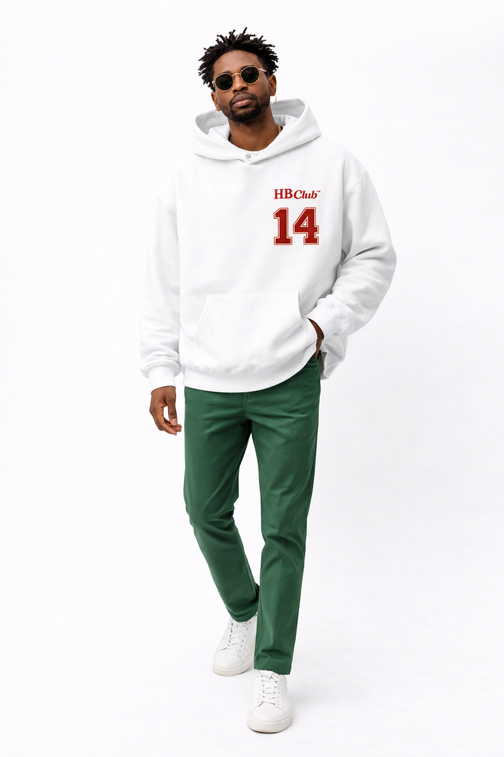 Male model in white oversized hoodie with small red “14” chest print, casual streetwear look with green trousers.