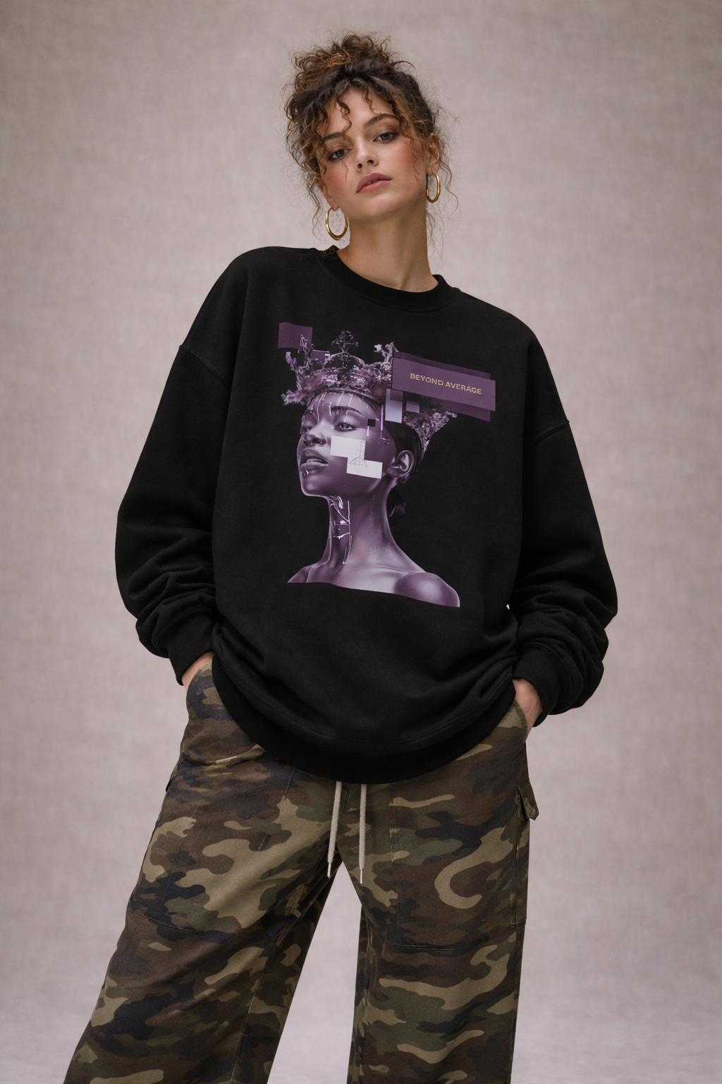 Woman wearing oversized black graphic sweatshirt with purple artistic portrait print, styled with camouflage cargo pants, modern women’s streetwear look.