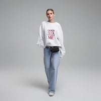 Model wearing white unisex graphic sweatshirt with bold “Good Luck Without Me” text, casual studio look