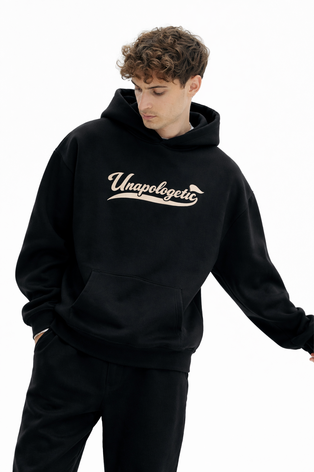 Noiré black oversized streetwear hoodie front view with “Unapologetic” script graphic in beige, worn by male model, unisex statement hoodie.