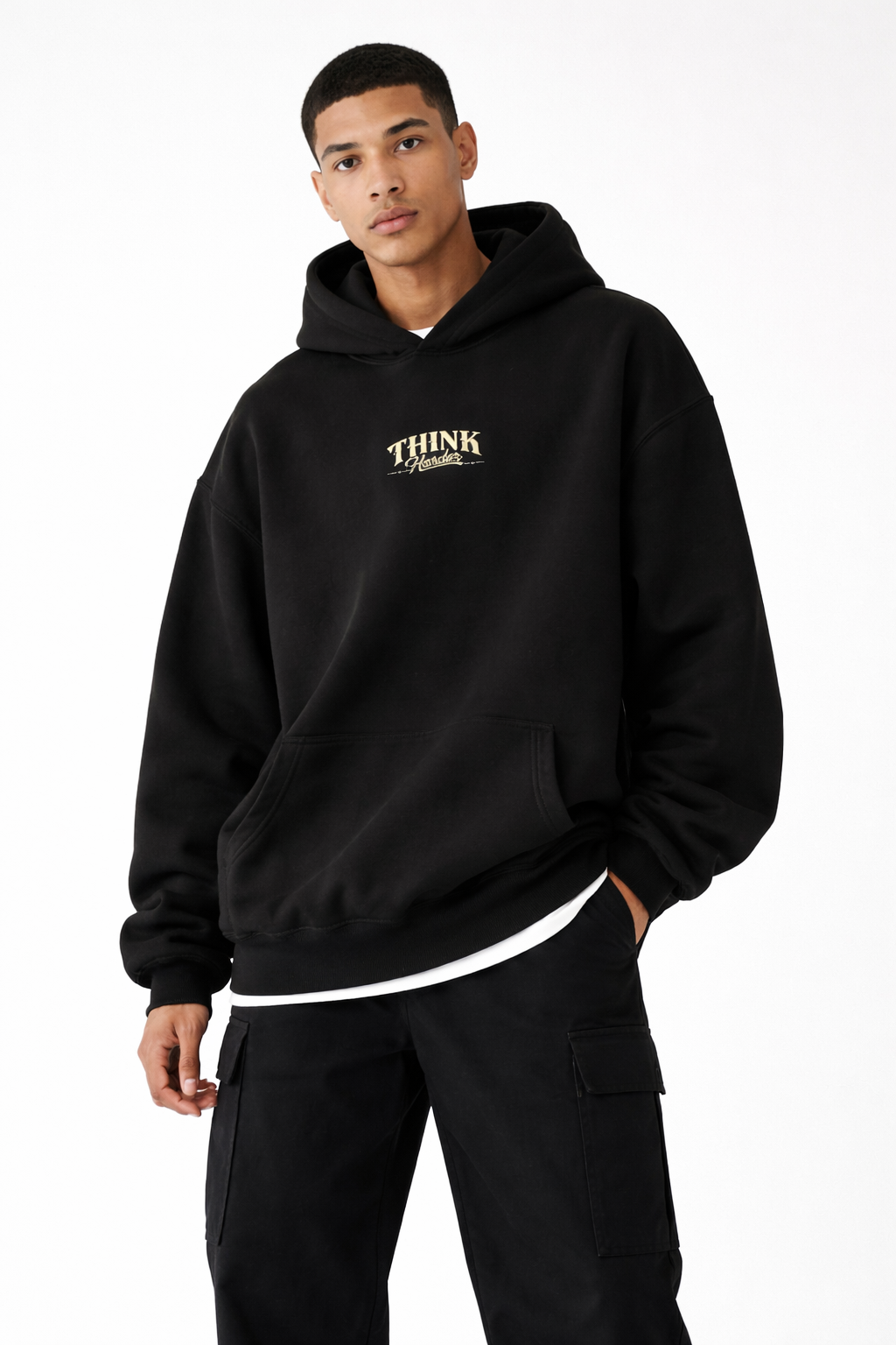 Male model in black oversized streetwear hoodie with minimalist chest detail, relaxed fit, studio setting.
