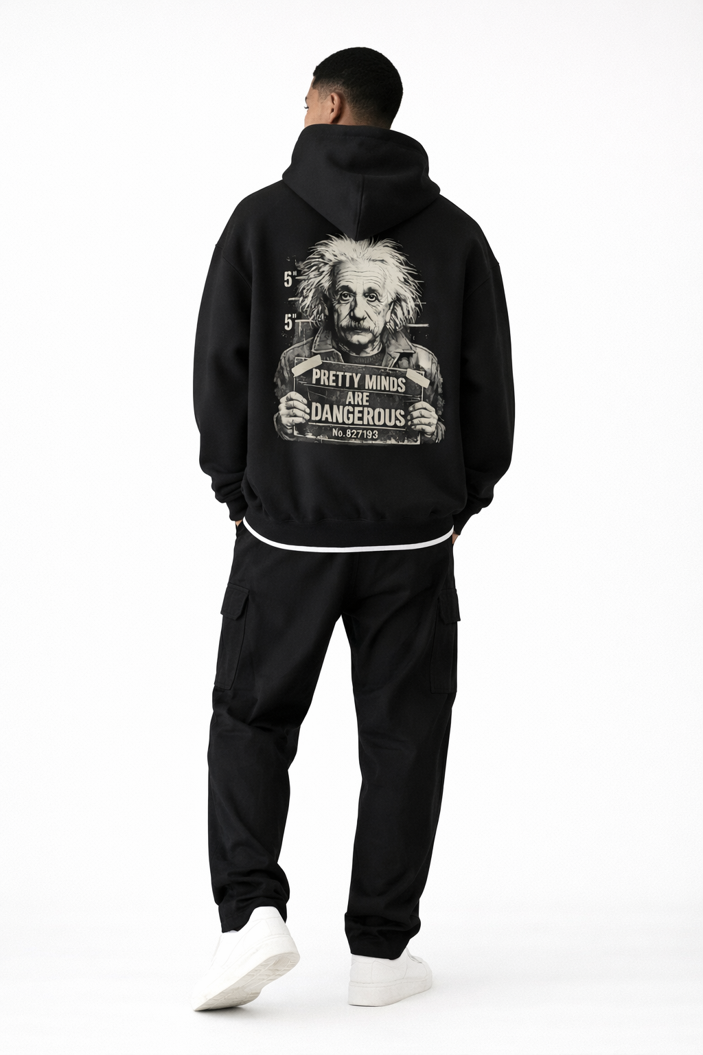 Back view of male model wearing black oversized hoodie with large back graphic print and statement typography, studio background.