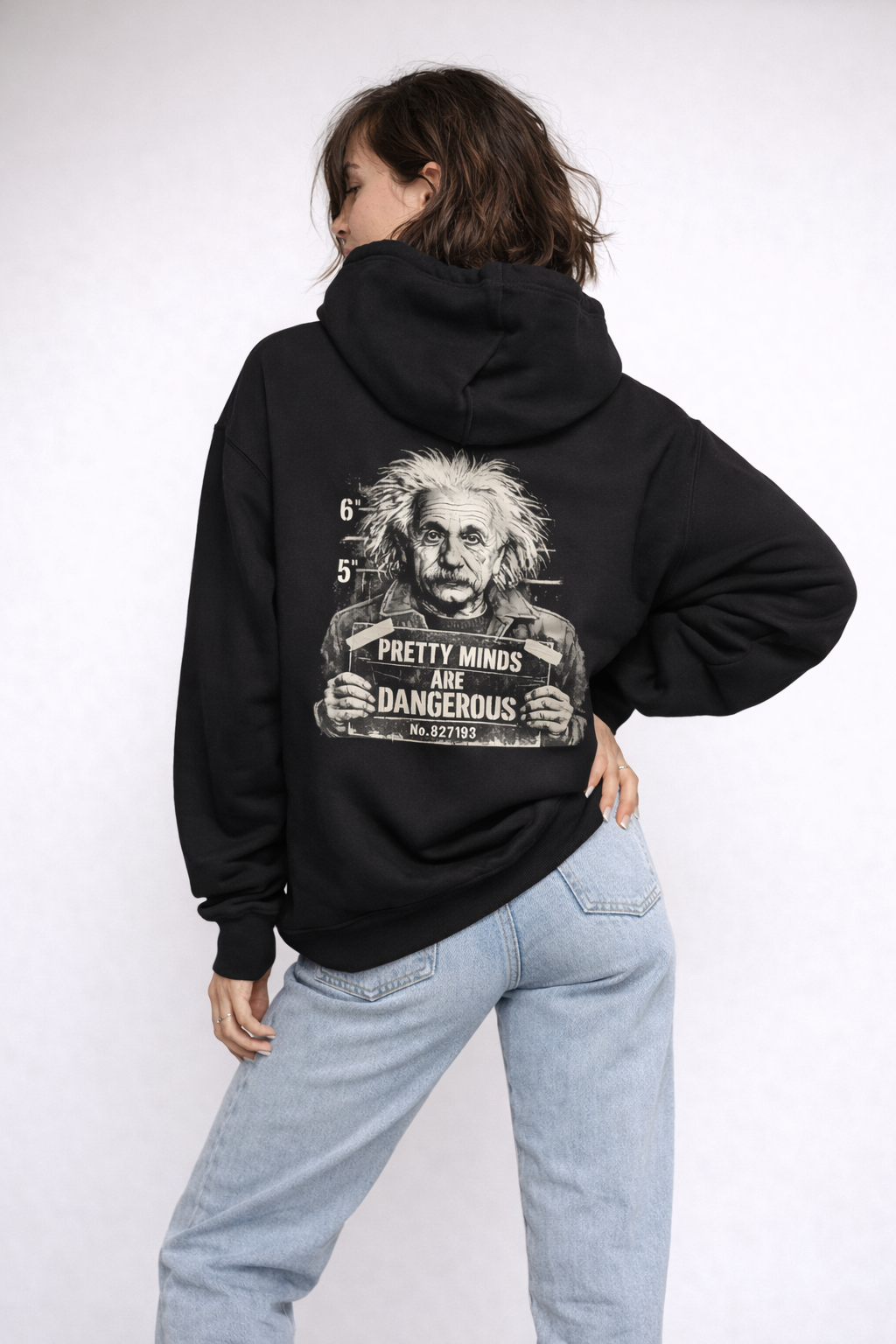 Female model back view wearing black oversized hoodie with bold back graphic design and statement print, streetwear aesthetic.