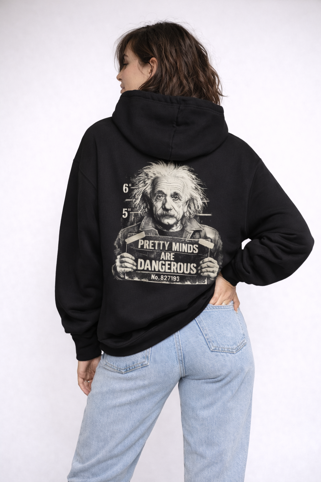 Female model back angled view in black oversized hoodie featuring large back graphic artwork, casual streetwear styling, studio background.