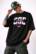 Black oversized Noiré T-shirt with bold “Where Is God Now” graphic and pink birds print, urban streetwear statement design.