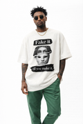 Beige oversized streetwear t-shirt “Fake it til you make it” with broken mask graphic print, male model wearing green pants, minimalist studio fashion photo