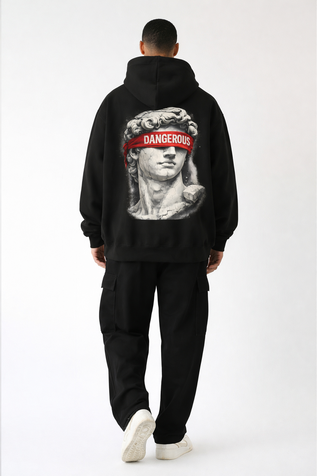 Black oversized hoodie back print with classical statue and bold red “DANGEROUS” lettering, male model full body studio image