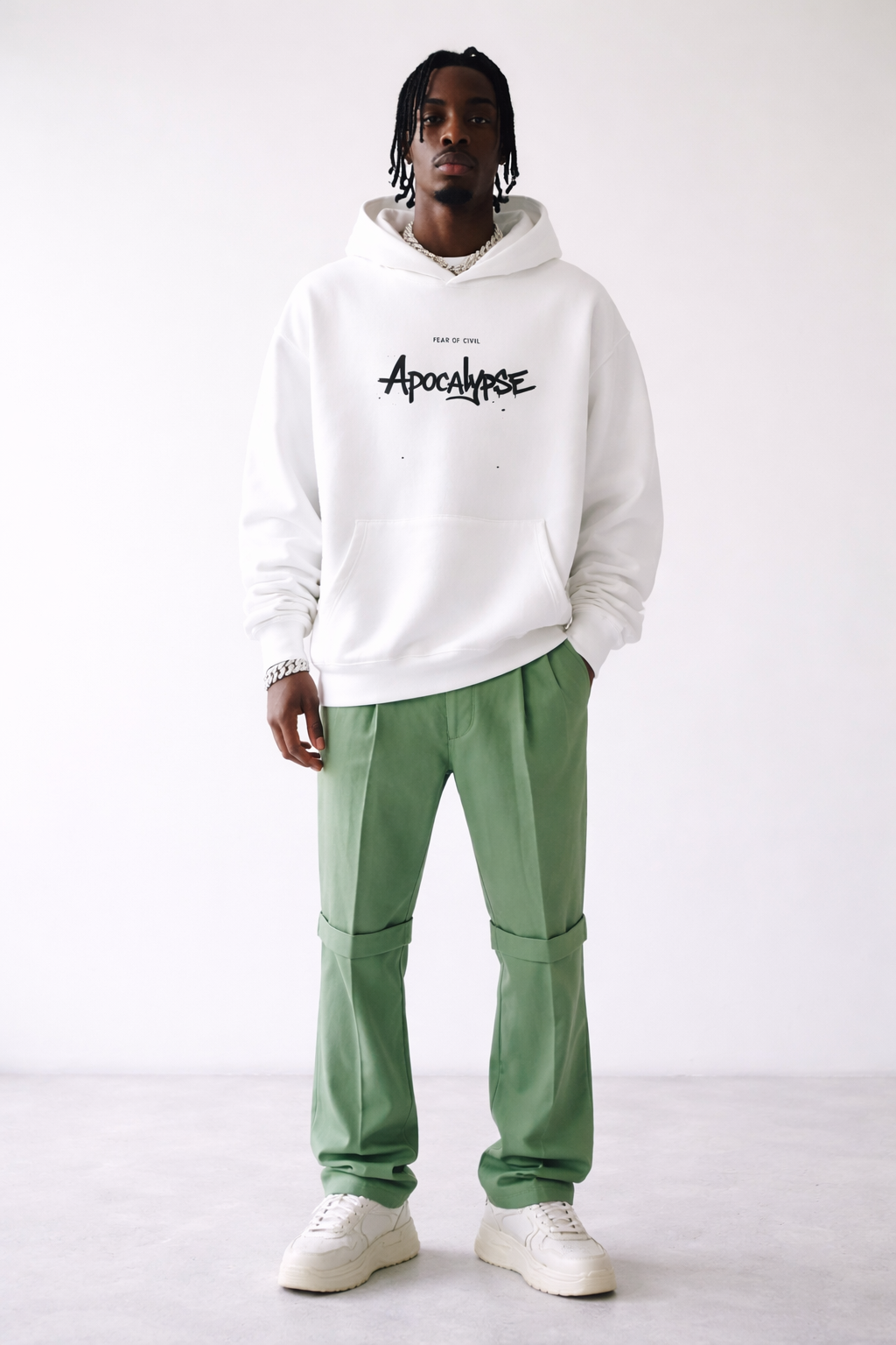 Men’s white oversized hoodie with “Apocalypse” graphic print on the front, modern streetwear sweatshirt styled with green pants, fashion product image.