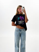 Model wearing black unisex graphic t-shirt with “Heck Off” portrait design, lifestyle studio photo