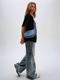 Model wearing black unisex graphic t-shirt with bold portrait artwork, casual lifestyle look