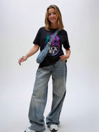 Model wearing black unisex graphic t-shirt with bold portrait artwork, casual lifestyle look