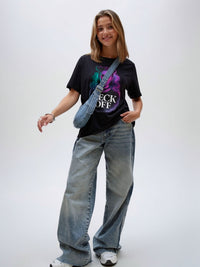 Model wearing black unisex graphic t-shirt with bold portrait artwork, casual lifestyle look