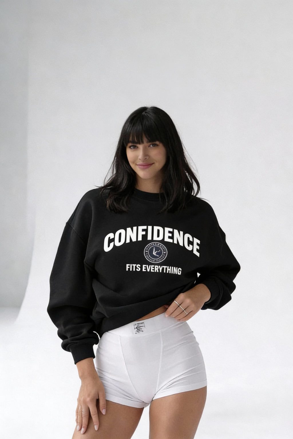 female model posing in black confidence fits everything sweatshirt white shorts front view
