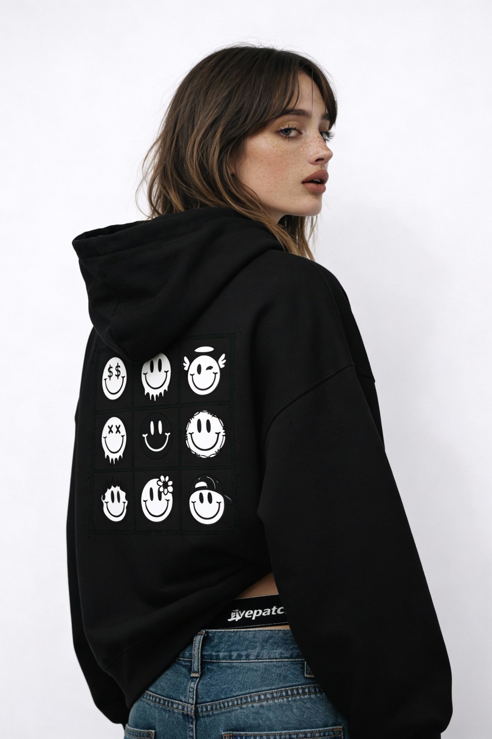 Noiré black oversized hoodie back view featuring bold 9-square smiley face graphic design, worn by female model, urban streetwear hoodie.