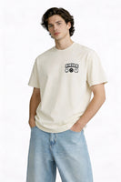Model wearing beige t-shirt with small “Smile” chest graphic, casual modern streetwear outfit by Noiré.