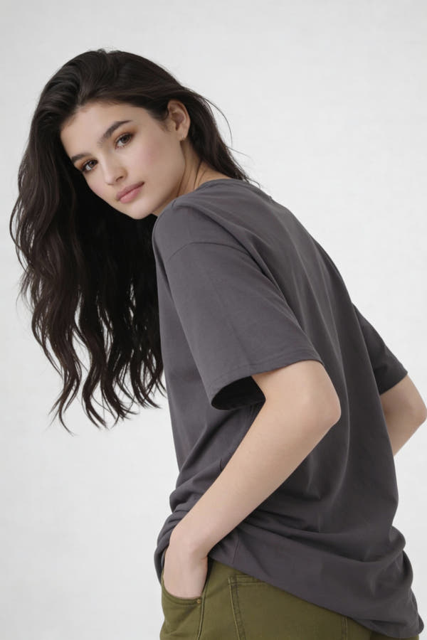 Model seen from back wearing dark grey oversized t-shirt , casual streetwear outfit by Noiré.