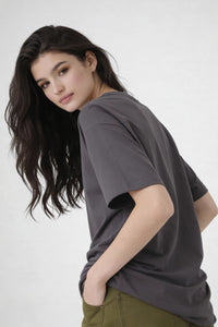 Model seen from back wearing dark grey oversized t-shirt , casual streetwear outfit by Noiré.