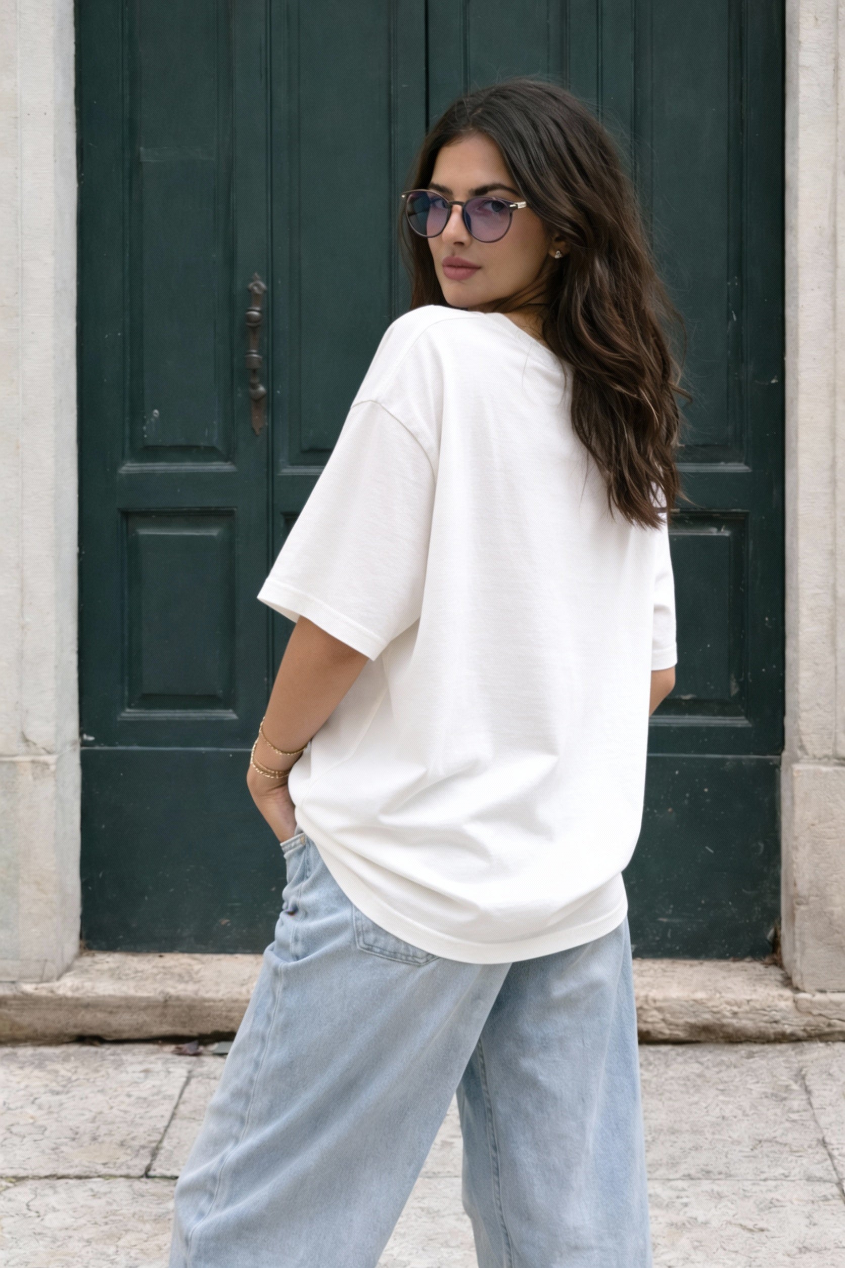 Female model seen from back wearing beige oversized t-shirt with minimal back design, modern streetwear look by Noiré.