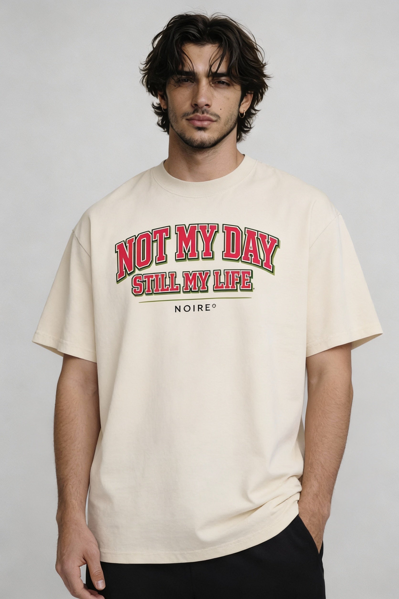 Male model wearing beige oversized t-shirt with red vintage typography print, casual streetwear look by Noiré.