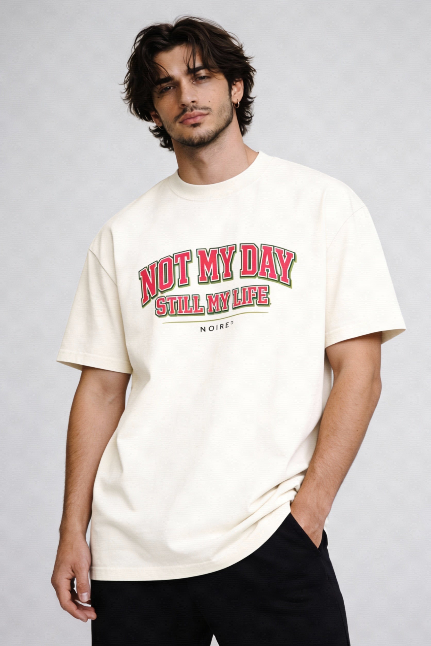 Male model wearing beige oversized t-shirt with red vintage typography print, casual streetwear look by Noiré.