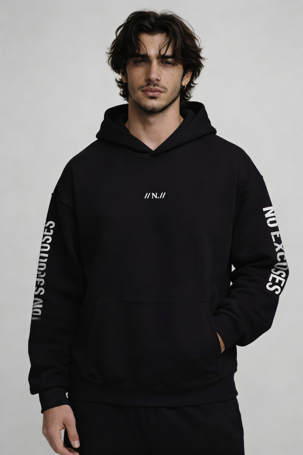 Noiré black oversized hoodie front view with minimalist chest logo “//N.//” and sleeve text “No Shortcuts” and “No Excuses” – men’s streetwear pullover