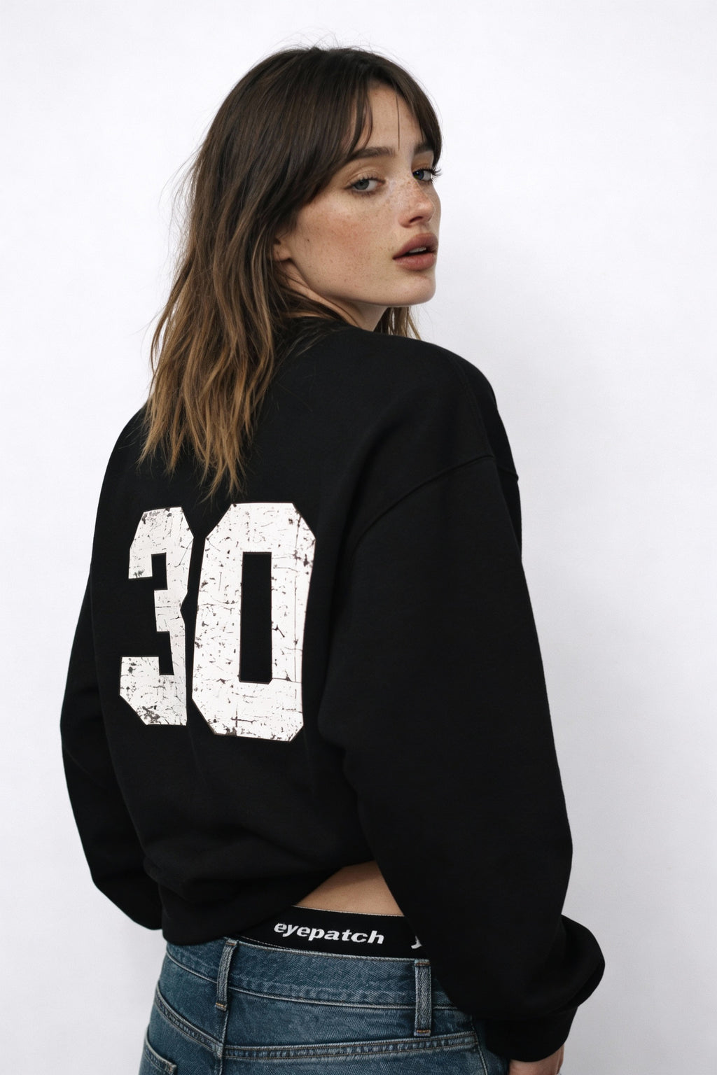 Noiré black oversized sweatshirt with vintage 30 back print, female model rear view, modern streetwear