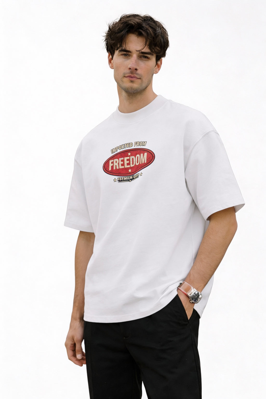 Man wearing white graphic T-shirt featuring “Imported From Freedom – Premium Goods” retro chest logo, minimal clean streetwear style, front view.