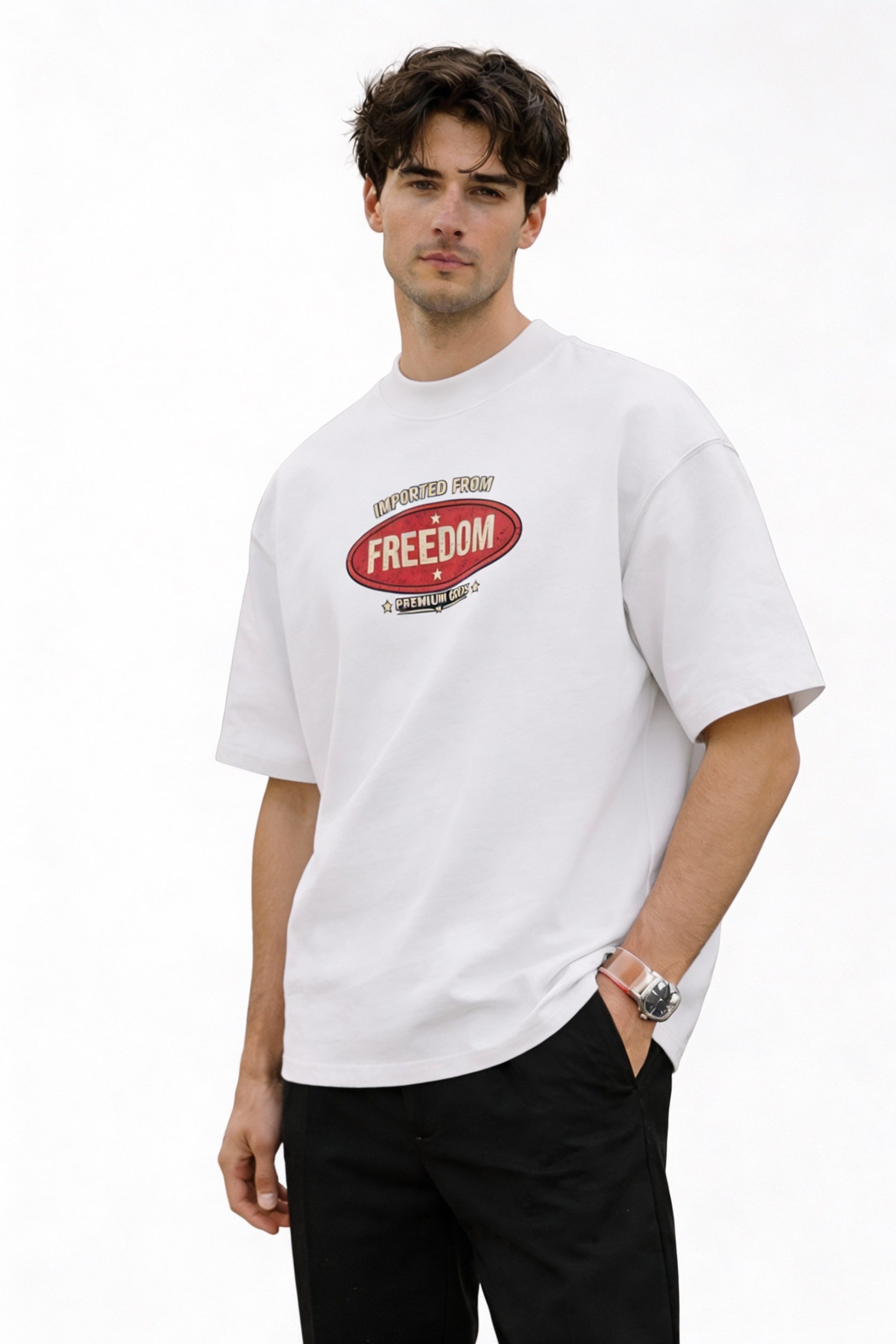 Man wearing white graphic T-shirt featuring “Imported From Freedom – Premium Goods” retro chest logo, minimal clean streetwear style, front view.