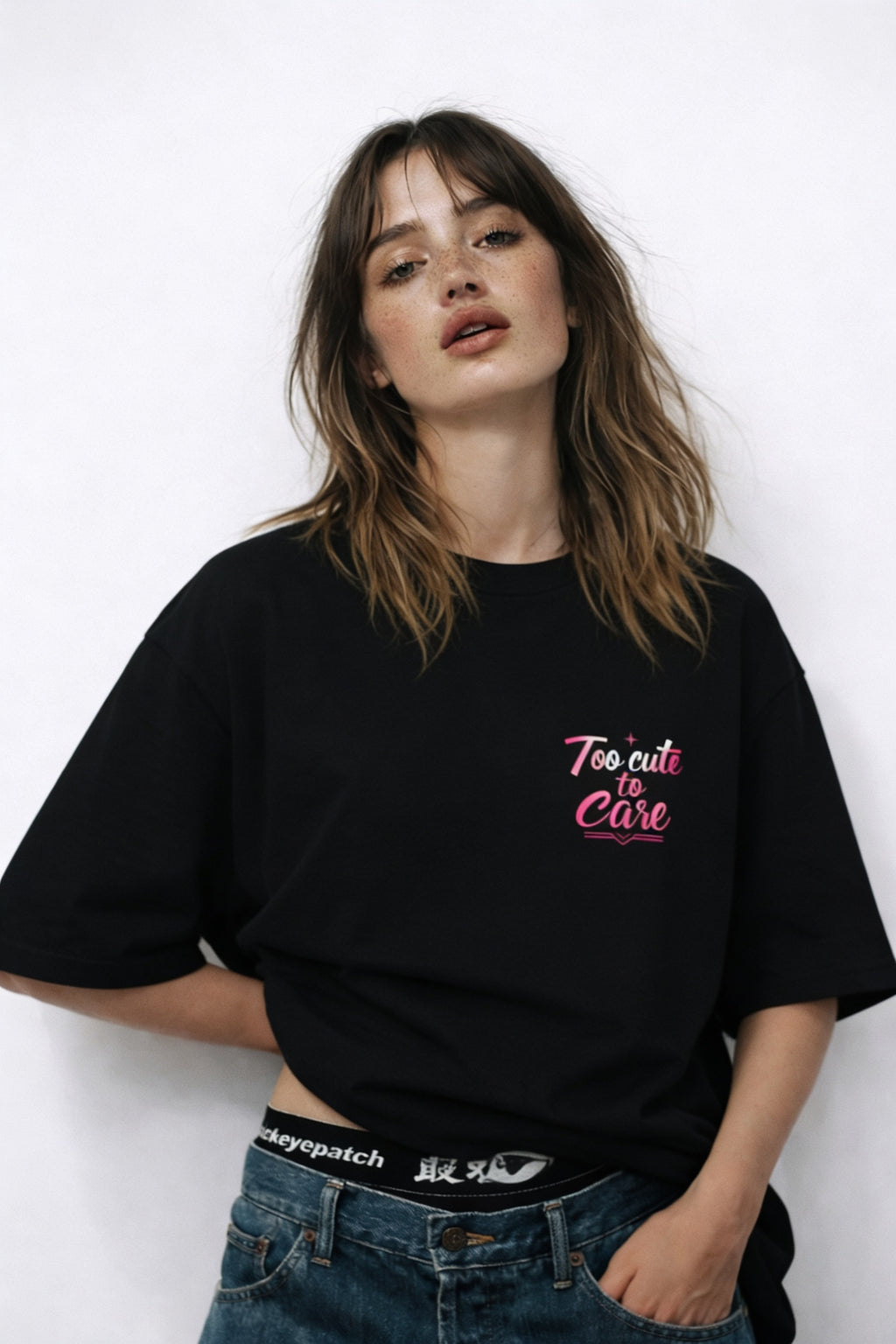 Woman wearing oversized black streetwear t-shirt with pink glitch portrait graphic and Too Cute To Care slogan