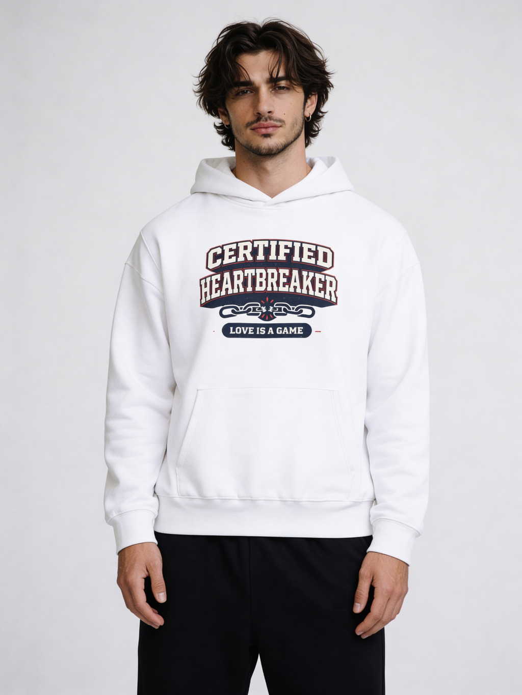 Noiré white oversized hoodie front view with “Certified Heartbreaker – Love Is a Game” varsity graphic print, worn by male model, streetwear Valentine drop.