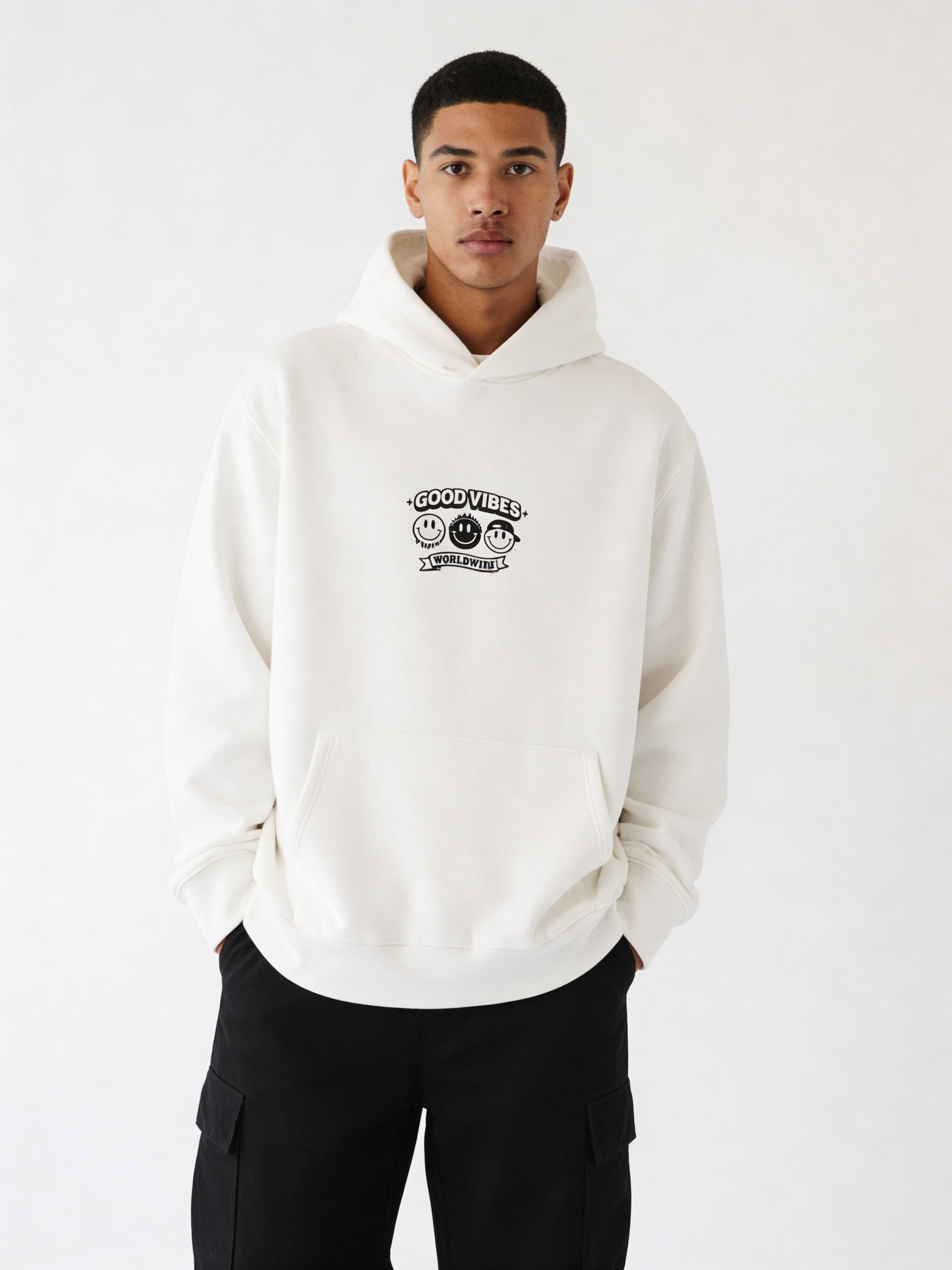 Noiré white oversized streetwear hoodie front view with “Good Vibes Worldwide” smiley logo print, worn by male model, unisex streetwear hoodie.