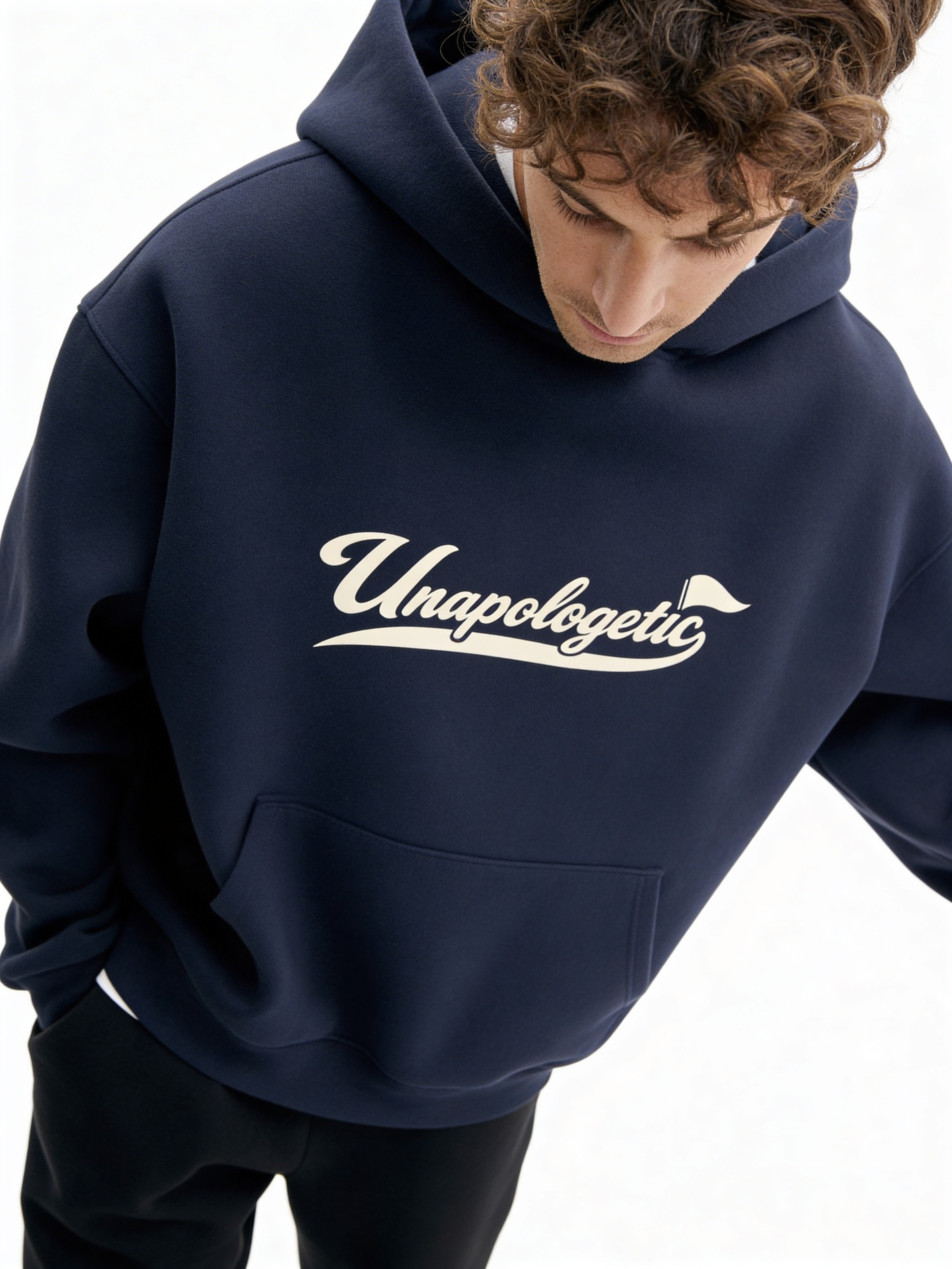 Noiré navy oversized streetwear hoodie front view with “Unapologetic” script graphic in beige, worn by male model, unisex statement hoodie.
