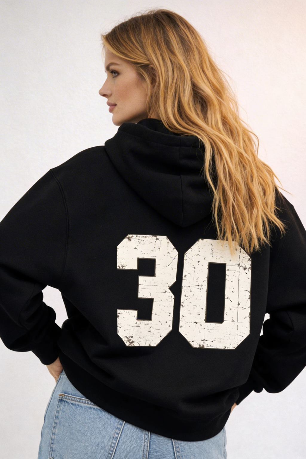 Noiré black oversized streetwear hoodie back view with large distressed “30” varsity number print, worn by female model, urban graphic hoodie.
