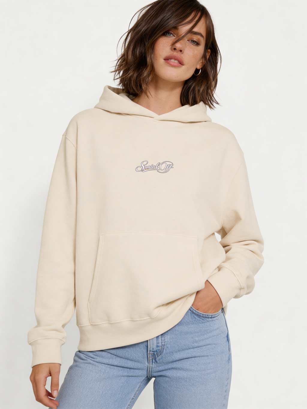 Noiré beige oversized streetwear hoodie front view with minimal “Social Off” script logo print, worn by female model, neutral aesthetic unisex hoodie.