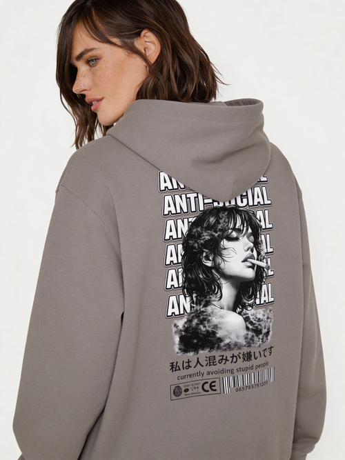 Noiré grey oversized hoodie back view with bold “Anti-Social” repeated typography and black and white portrait graphic, worn by female model, statement streetwear hoodie.